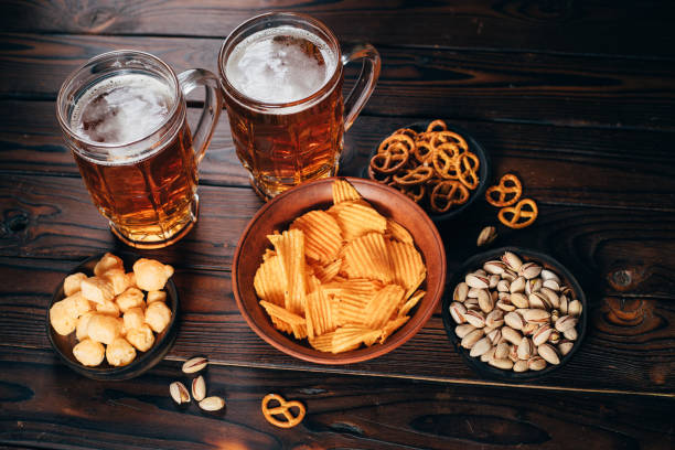 Chips, pretzels, nuts and two mugs of lager Variety of snacks and mug of light beer. Chips, pretzels and nuts with two mugs of lager. Bar table. Restaurant, pub, Beer Fest food biscuit quick bread photos stock pictures, royalty-free photos & images