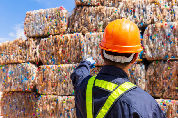 istock Foreman or engineer wearing protective clothing Currently ordering at a plastic recycling plant. Engineer and recycle. Engineers standing in recycling center. 1212693156