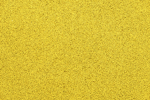 Soft protective yellow rubber crumb coating. Texture of a safe rubberized surface for playgrounds and sports fields. Close-up top view
