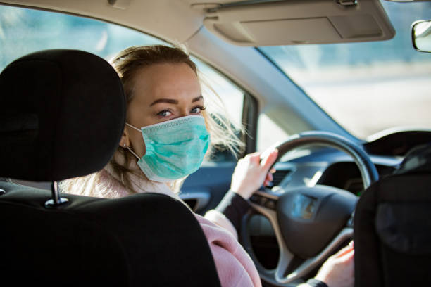 istock Woman in protective mask driving a car on road. 1212696719