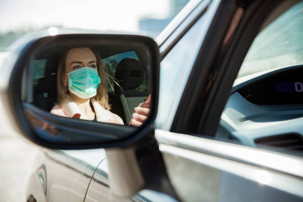 donna in maschera protettiva alla guida di un'auto su strada. - driving women rear view sitting foto e immagini stock