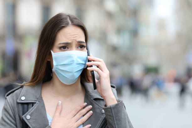 istock Scared girl with mask calling on phone on street 1212698079