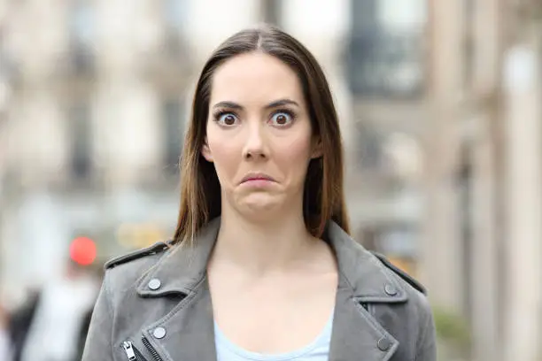 Photo of Shocked woman looking at camera on city street