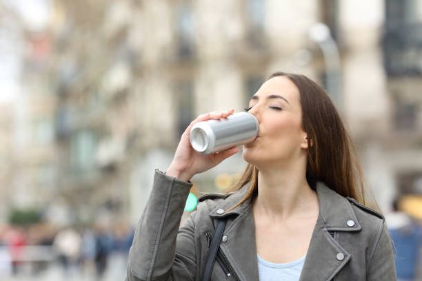 Woman drinking a refreshment from can Woman drinking a cold refreshment from a blank aluminum can in the street woman drinking beer stock pictures, royalty-free photos & images
