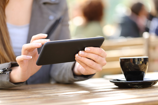 Close up of woman hands watching videos on her smart phone on a cafe terrace