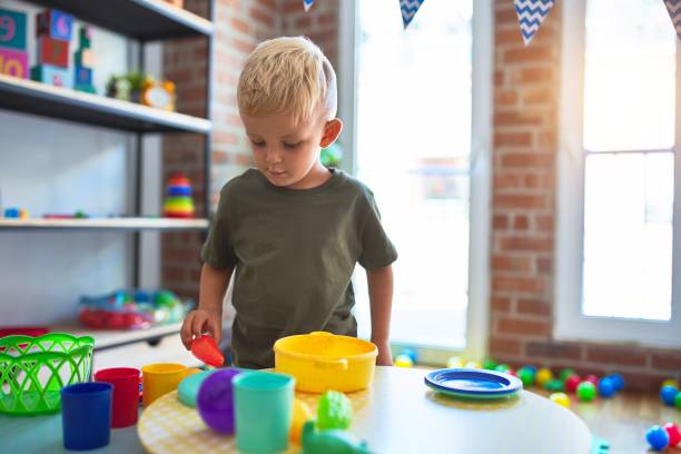 istock Young caucasian kid playing at kindergarten with toys kitchen. Preschooler happy boy doing cooking. 1212698607