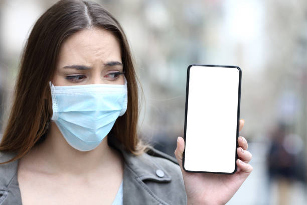 istock Scared girl with mask looking at blank phone screen 1212699868