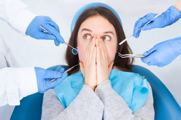 Young female woman patient at dentist office Closeup doctor hands in gloves are holding dental instruments in clinic, office. Scared woman is closing her mouth with hands, preventing examining of teeth, because of fear. Visiting dentist concept. phobia stock pictures, royalty-free photos & images
