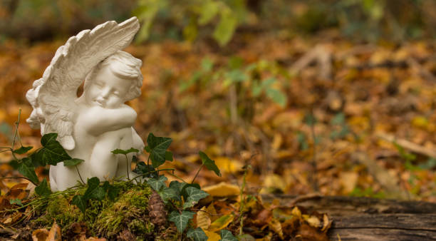 Urn grave with angel, forest cemetery Forest cemetery, white angel nature funeral, copy space pics of guardian angels stock pictures, royalty-free photos & images