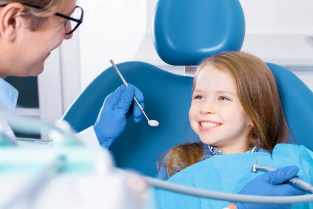 Young child girl check out teeth at dentist office Little cute smiling girl is sitting in dental chair and opening mouth in clinic, office. Doctor is preparing for examination of child teeth with tools, instruments. Visiting dentist with children. pediatric dentistry stock pictures, royalty-free photos & images