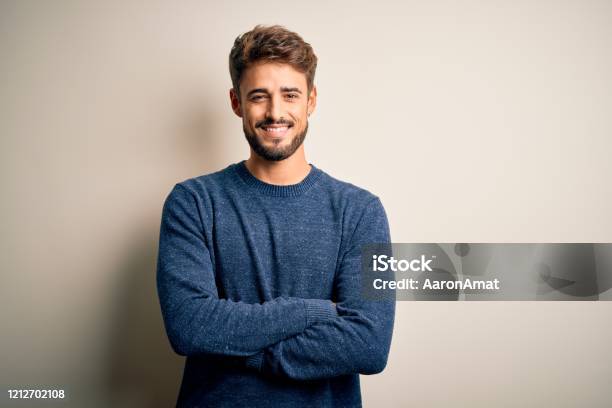 Young Handsome Man With Beard Wearing Casual Sweater Standing Over White Background Happy Face Smiling With Crossed Arms Looking At The Camera Positive Person Stock Photo - Download Image Now