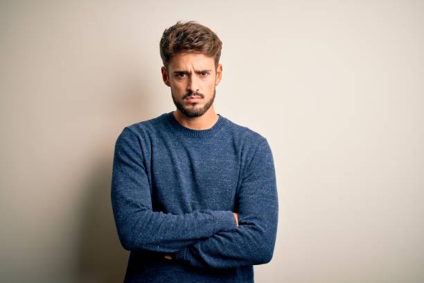 istock Young handsome man with beard wearing casual sweater standing over white background skeptic and nervous, disapproving expression on face with crossed arms. Negative person. 1212702152
