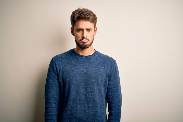 istock Young handsome man with beard wearing casual sweater standing over white background depressed and worry for distress, crying angry and afraid. Sad expression. 1212702164