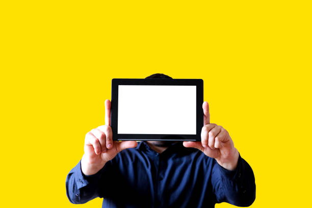 Man holding a tablet in hands. Screen instead of face. New technologies communication. Copy space place. Isolated on yellow background.