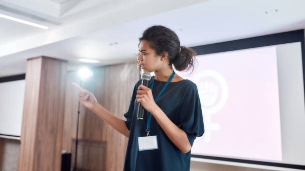 istock Focus on the Future. Female speaker with microphone giving a powerful talk on corporate business meeting 1212705112