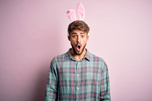 istock Young handsome adult man wearing cute easter rabbit ears over pink isolated background afraid and shocked with surprise expression, fear and excited face. 1212707609