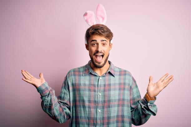 istock Young handsome adult man wearing cute easter rabbit ears over pink isolated background celebrating crazy and amazed for success with arms raised and open eyes screaming excited. Winner concept 1212707664