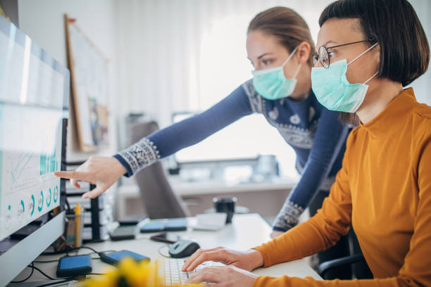 Two colleagues at work wearing face protective mask, to protecting themselves against corona virus