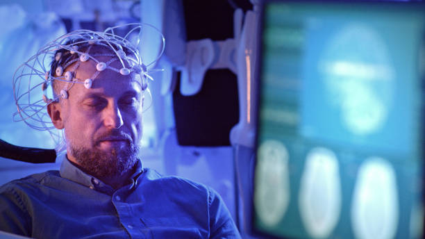 Man Wearing Brainwave Scanning Headset. In modern Neurological Research Laboratory. EEG animation on monitor screen. neuron schema stock pictures, royalty-free photos & images