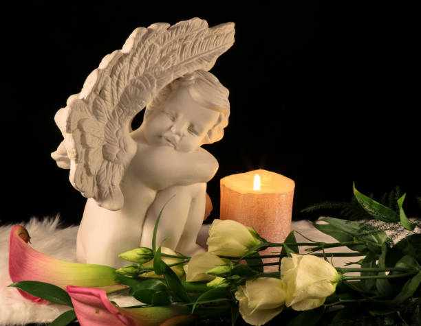 istock Angel and white candle on dark background 1212709187