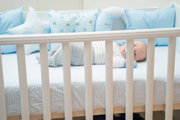 istock Cute baby lying in his crib sucking on pacifier 1212709210