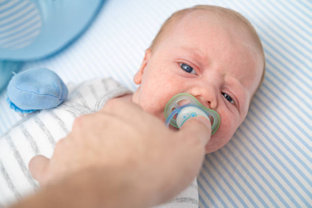 istock Hand holding giving pacifier to baby boy close-up 1212709417