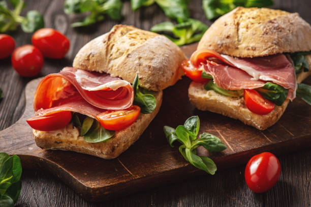 istock Jamon sandwiches with tomatoes, on wooden board. 1212710672