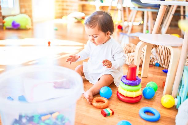 カラフルなおもちゃの周りの幼稚園で幸せな美しい幼児 - block child play toy ストックフォトと画像