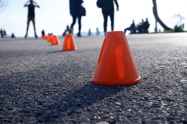 The image captures a young rollerblader skillfully maneuvering past colorful cones set up on a smooth pavement in an outdoor space, emphasizing movement and agility during practice.