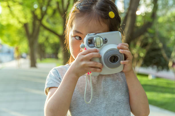 istock an Asian kid having fun with an instant camera in nature 1212723031