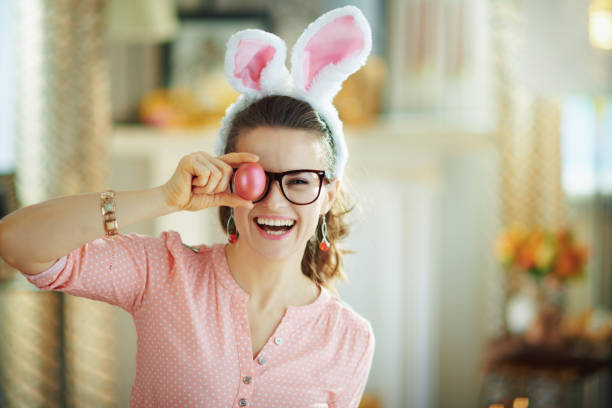 szczęśliwa młoda kobieta w okularach pokazujących czerwone jajko wielkanocne - city of post zdjęcia i obrazy z banku zdjęć