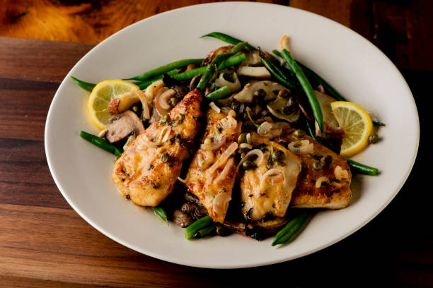 chicken piccata. chicken breast breaded, fried topped with mushroom and marsala wine sauce then served with angel hair pasta and dressed in olive oil. classic italian entree favorite. - parmesan cheese chicken veal salad imagens e fotografias de stock