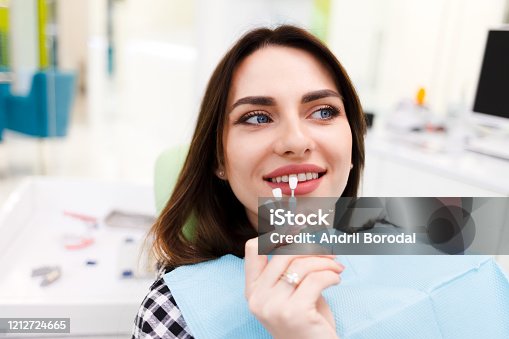 istock Girl chooses color of veneers at the dentist office 1212724665