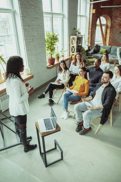 istock Female african-american speaker giving presentation in hall at university workshop 1212725342