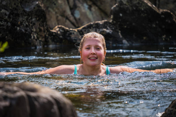 istock Woman wild swimming in cool mountain stream wilderness 1212727332