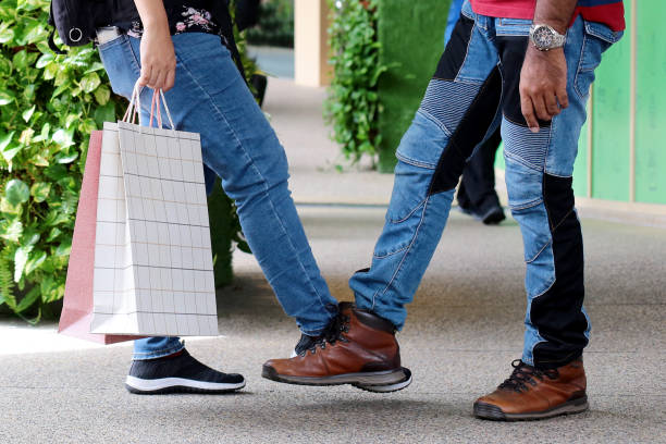 A modern Muslim man tapping his wife's shoe while enjoying shopping in Malaysia as a gesture of alternative physical contact in their relationship.