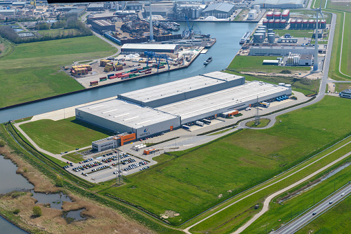 Aerial view on the Zuiderzeehaven industrial area in the city of Kampen, The Netherlands, with a warehousee in the foreground and storage containers and a breakers yard in the background.