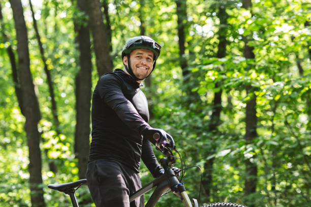 istock Young athletic cyclist smiling at camera, green forest 1212728691