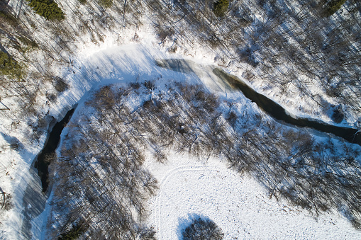 Beautiful Sunny landscape with forest, snow and frozen river. Aerial photography from a drone.