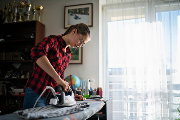 adolescente che stira i vestiti a casa - iron laundry cleaning ironing board foto e immagini stock