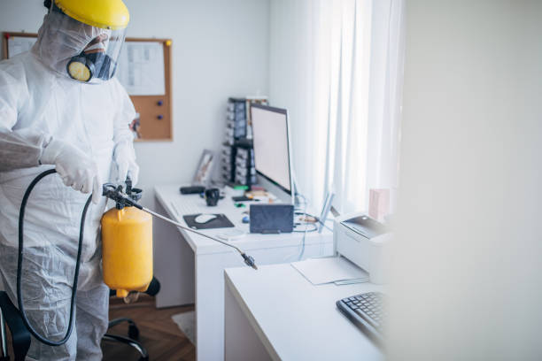 un uomo in tuta protettiva che disinfetta lo spazio di lavoro d'ufficio - protective suit foto e immagini stock