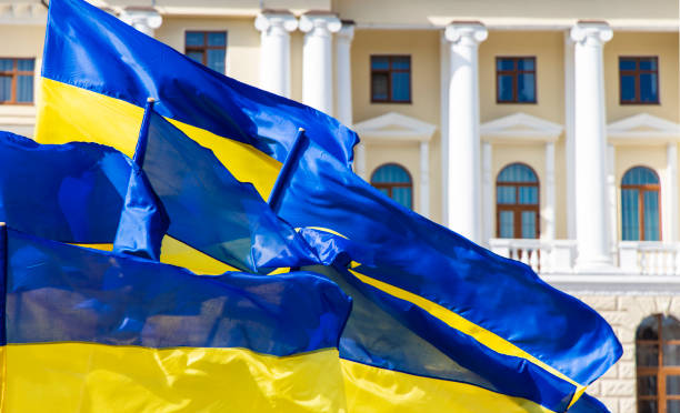 Ukraine blue yellow flags evolving on a wind near town hall classic architecture building with columns arch windows and soft pink and white walls, independence and revolution of dignity concept