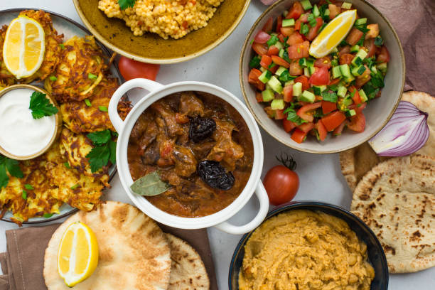 Israeli cuisine: esik fleisch - beef stew with damson plums and spices, hummus,  potato latkes, ptitim, a type of pasta also known as "Israeli couscous", pita bread, israeli salad. White background