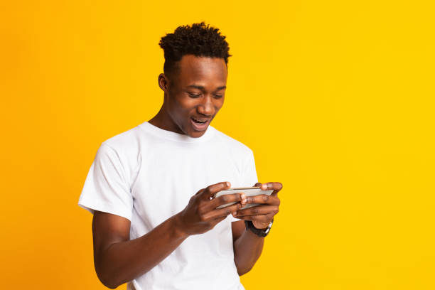 istock Joyful african american man using cellphone on yellow 1212740728