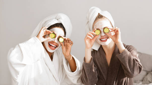 istock Girlfriends in bathrobes and face masks covering eyes with avocado 1212741364