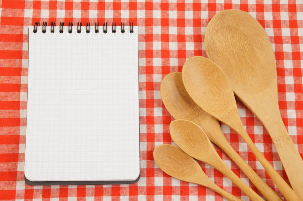 istock Wooden spoons on red tablecloth with blank note pad 1212741734