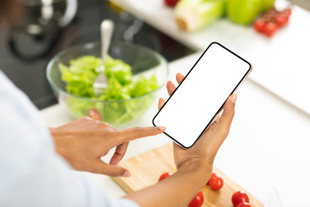 Black girl using smartphone with blank screen in the kitchen