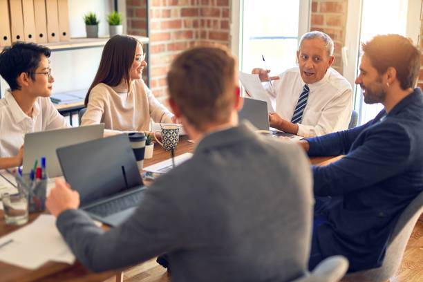 istock Group of business workers working together. Sitting on desk using laptop reading documents at the office 1212741908