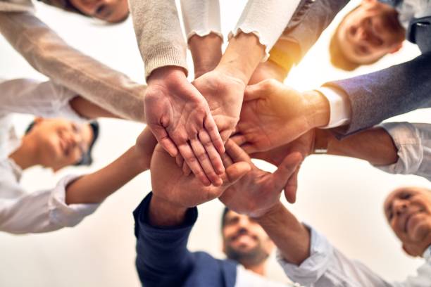 istock Group of business workers standing with hands together at the office 1212742293