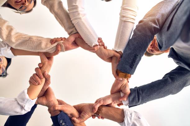 istock Group of business workers standing with hands together at the office 1212742312